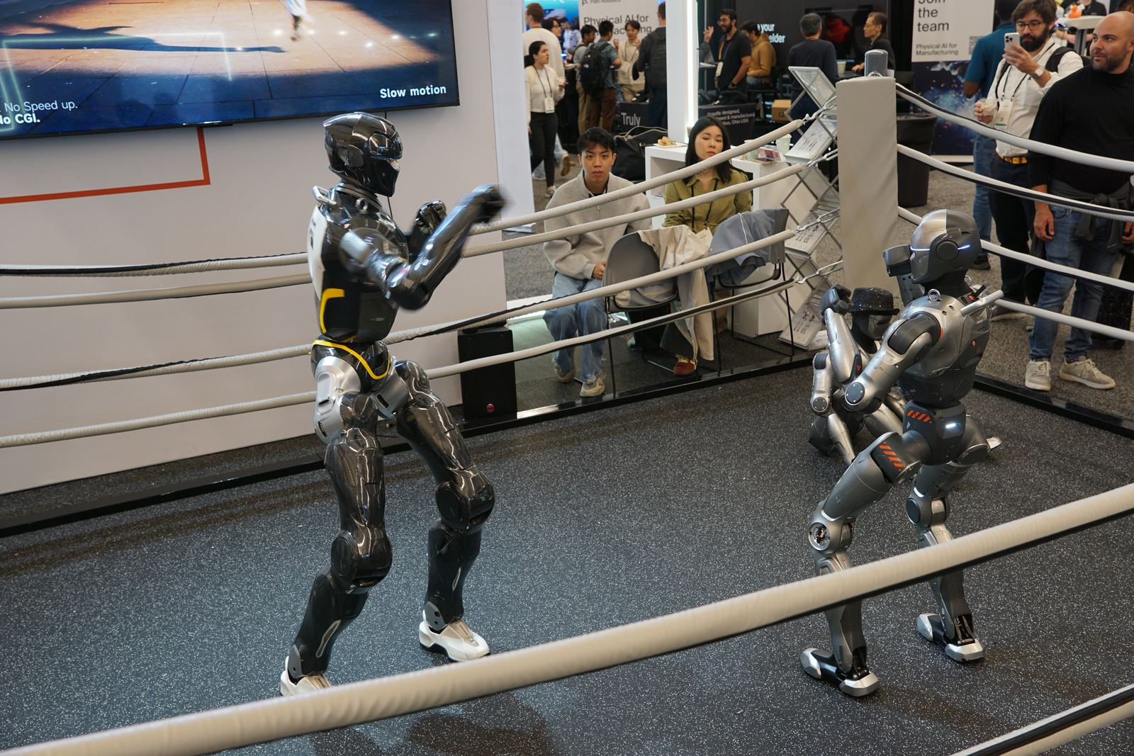 EngineAI humanoids boxing in a ring on the exhibit floor.